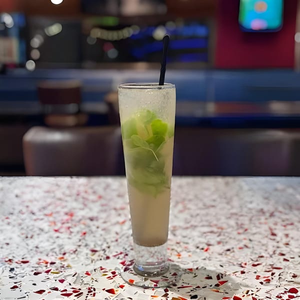 Tall glass of a refreshing Masthi Bar & Grill drink with mint leaves and a straw.