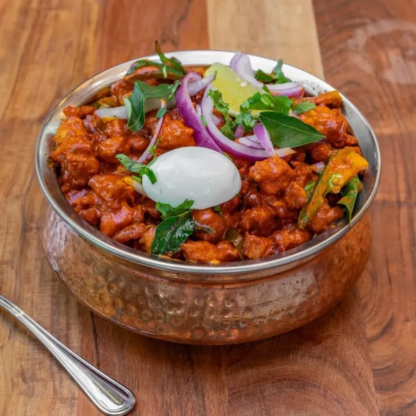 Masthi Bar & Grill's Indian chicken dish, garnished with onions, lime, and a dollop of white sauce.