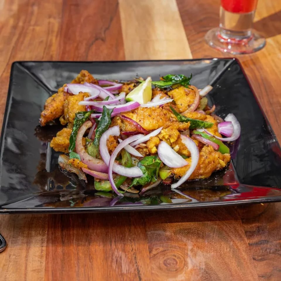 Masthi Bar & Grill's Indian appetizer, featuring fried chicken, red onions, green peppers, and a lime wedge.